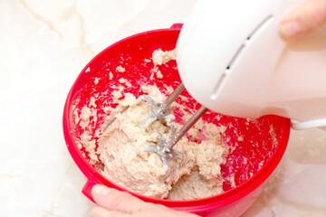 Hands mixing dough in a bowl with electric beater