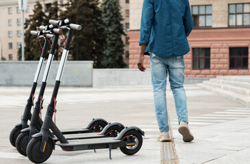 Guy standing near rental motorized kick scooters