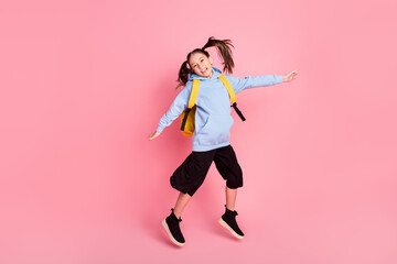 Full length body size photo of jumping girl wearing track suit yellow backpack isolated pastel pink color background