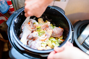 raw chicken legs and vegetables are mixed in a non-burner multicooker bowl