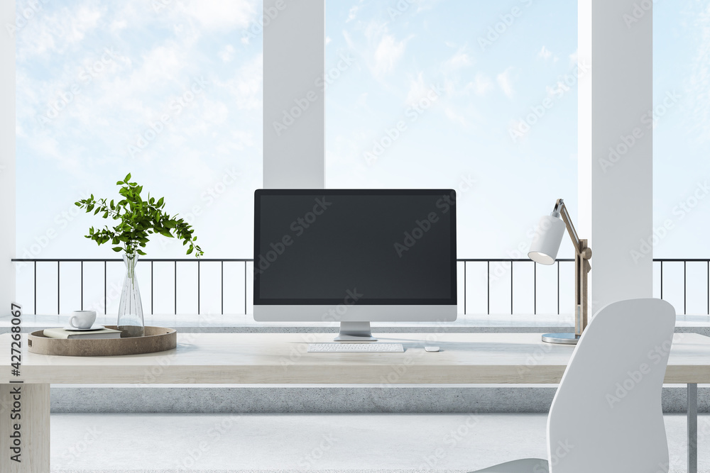 Poster pc standing on a desk in a bright room with columns and big windows, black desktop, front view. work
