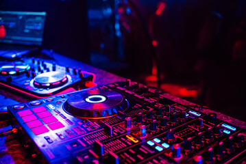 Plakat DJ console for mixing music with blurry people dancing at a nightclub party