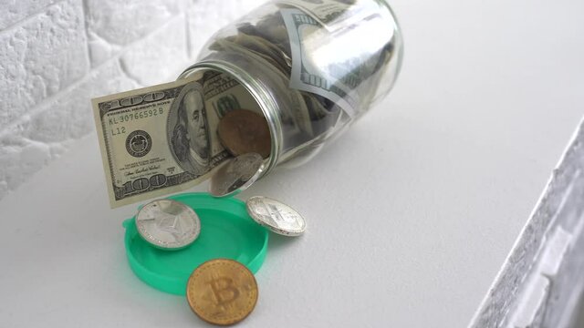 Saving money coin in jar. Symbol of investing, keeping money concept. Collecting cash banknotes in glass tin as moneybox. American dollars close-up with increasing columns of gold coins on black table