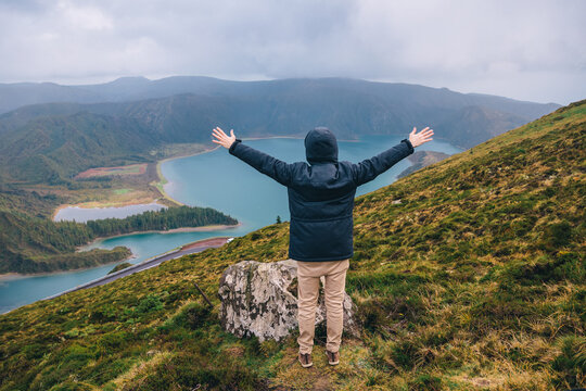 "Lagoa do Fogo" on the island of São Miguel, Azores. The man stands with his back, arms outstretched joyfully to the sides. welcome gesture.