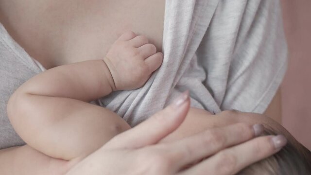 asian woman mother breastfeeding baby infant at home. parent holding daughter giving breast milk. mother embrace baby in arm. life at home. touching hand and head gently. newborn hand holding parent.