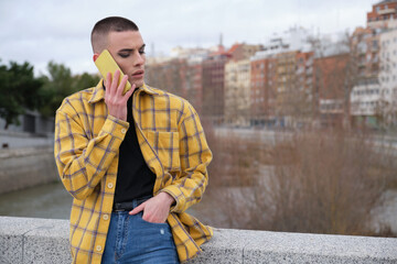 Young non binary person speaking on a smartphone annoyed. Make up androgynous person.