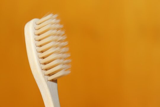 A natural bamboo toothbrush on bright orange background. A concept of wellness and zero waste. Say no to plastic. Stock photo with copy space