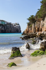 Fototapeta na wymiar Beautiful sunny day at the beach with crystal clear turquoise water surrounded by cliffs. Cala en Porter, Menorca.