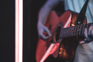 Close up of a guitarist playing an acoustic guitar in a dark room.