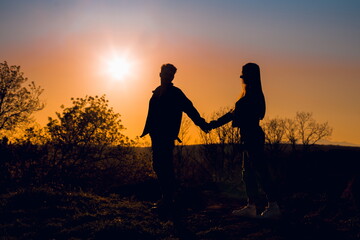 Naklejka na ściany i meble Silhouette of couple holding hands at sunset