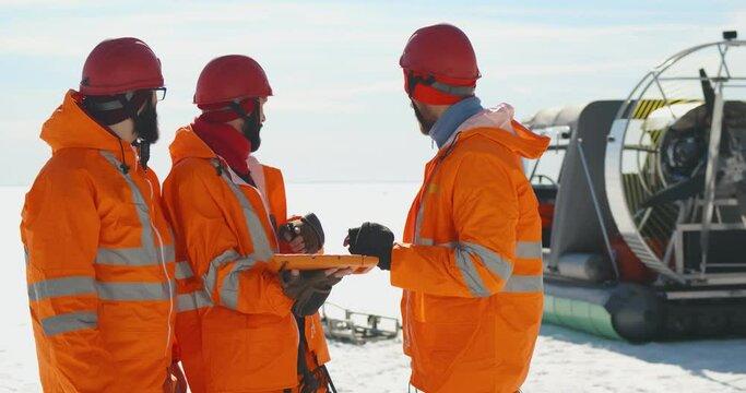 Lifesaving team discussing patrol route on digital tablet standing in arctic