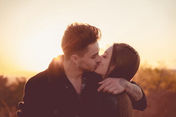 Couple kissing at sunset with the sun behind them