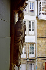 Escultura románica en las jambas de una iglesia, con edificios de apartamentos al fondo propios del casco antiguo de la ciudad de La Coruña, España