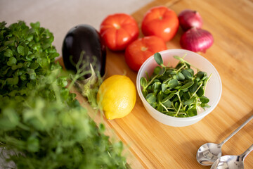 selective focus. Kitchen table and wooden board with ingredients for cooking healthy food, salad of tomato, eggplant, onion, microgreen peas and sunflower. dressing with lemon juice