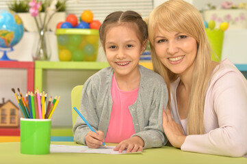 little cute girl with mother drawing  at home