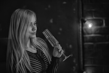 sexy blonde girl drinks champagne from a glass, evening glamorous style portrait