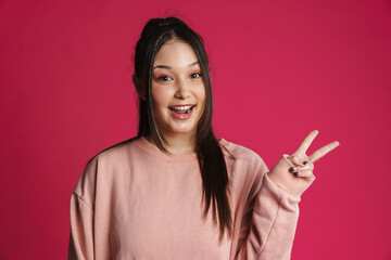 Asian brunette woman smiling and gesturing peace sign