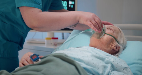 Nurse putting oxygen mask on aged patient 