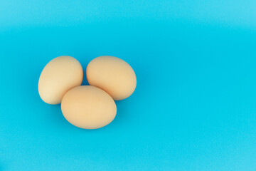 three chicken egg on a blue background, place for text