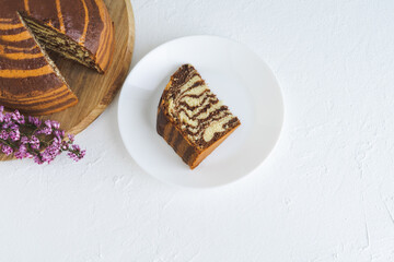 Zebra cake on white background. Piece of sponge cake on white plate. Copy space.