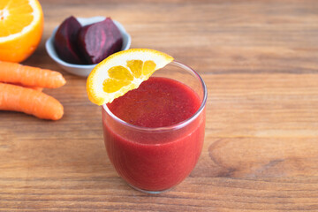 Beet juice glass on wooden bottom with orange slices decoration. Copy space.