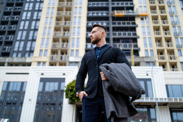 Stylish male standing on urban street. Portrait of handsome young man posing for camera.