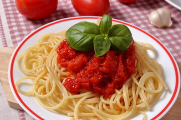 Piatto di spaghetti con salsa di pomodoro e foglie di basilico fresco.