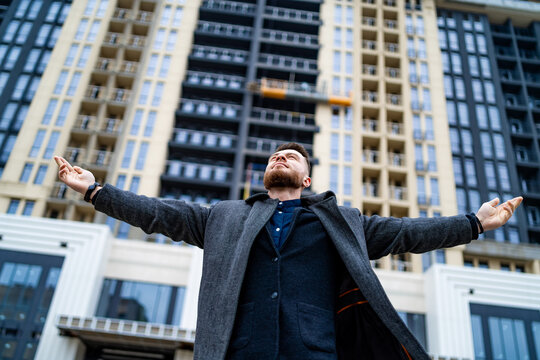 Excited young businessman raised arms. Successful worker celebrating wining. Feeling of freedom and relaxation.