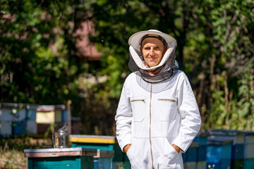 Handsome man working beekeeping with hive. Harvesting beeswax in sunny summer.