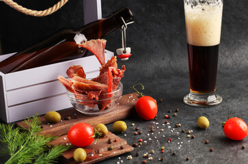 Dried meat slices with spices in a glass cup on a dark background. Condiments and coarse salt, red...