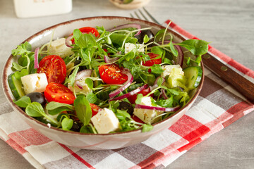 Greek salad of fresh cucumbers, tomatoes, sweet peppers, lettuce, red onion, feta cheese and olives with olive oil.
