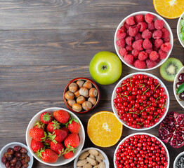 Mix of fresh berries, nuts and fruits. Healthy food contains a lot of vitamins and useful trace elements.Brown wooden background. Copy space.