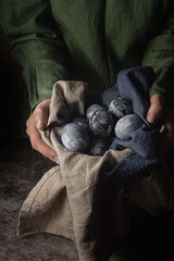 female hands hold a clay cup with marble painted eggs for Easter. A method for dyeing eggs with natural blueberry juice dye. country style.