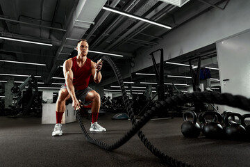 Sport. Strong man exercising with battle ropes at the gym with. Athlete doing battle rope workout...