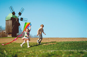Obraz na płótnie Canvas Happy kid boy and girl playing with kite over wind turbine farm and green renewable energy. Concept of sustainability development by alternative energy. Children and wind.