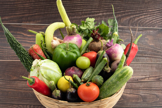 Healthy Vegetarian Food - Variety Of Farm Fresh Organic Green Vegetables  Like Karela Lauki Kaddu Ghiya Bhindi Gobi Chukandar Baingan Tamatar Amla Neembu Parwal In Bamboo Basket On Wooden Background