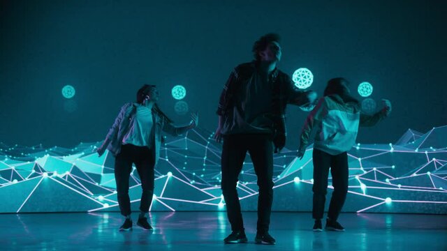 Diverse Group of Three Professional Dancers Performing a Hip Hop Dance Routine in Front of a Big Led Wall Screen with VFX Animation During a Virtual Production in Studio Environment. 105 BPM Song.