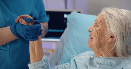 Medical doctor holing senior patient hand and comforting her