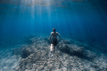 Male freediver glides underwater in blue sea - obrazy, fototapety, plakaty