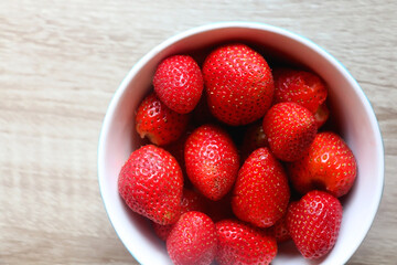 Bowl of fresh strawberries on a table. Flat lay.