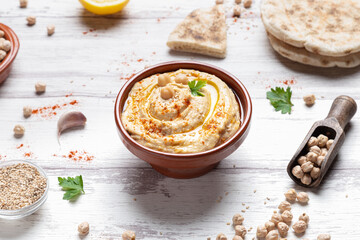 Bowl of homemade hummus on light background.