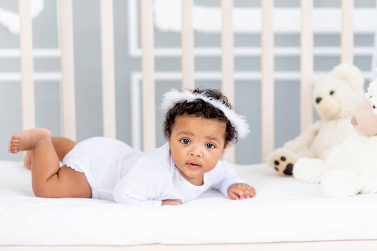 cute African-American little baby lying in bed for sleeping with angel headband