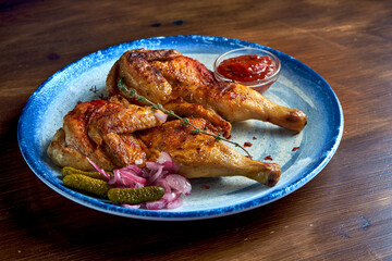 Georgian cuisine dish chicken tapaka or tabaka on a plate, on wooden background. Grilled chicken. close up
