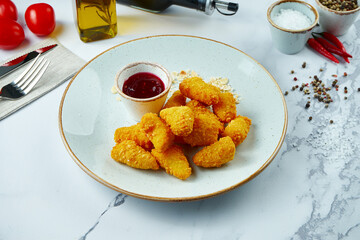 Fried Camembert cheese in breading with cranberry sauce in a white plate, in a composition on a light background. Deep-fried crispy cheese, appetizer.