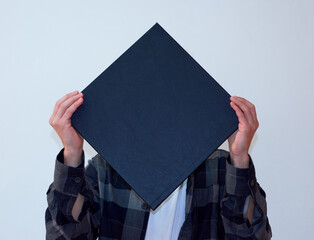 A young man covering his face with a folder isolated on a white background