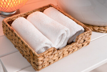 Three white towels close-up, stacked in a bamboo wicker basket. Spa care. massage, rest and relaxation concept. Lifestyle. top view