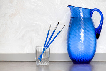 Blue jug with drinking water and brushes on white background.