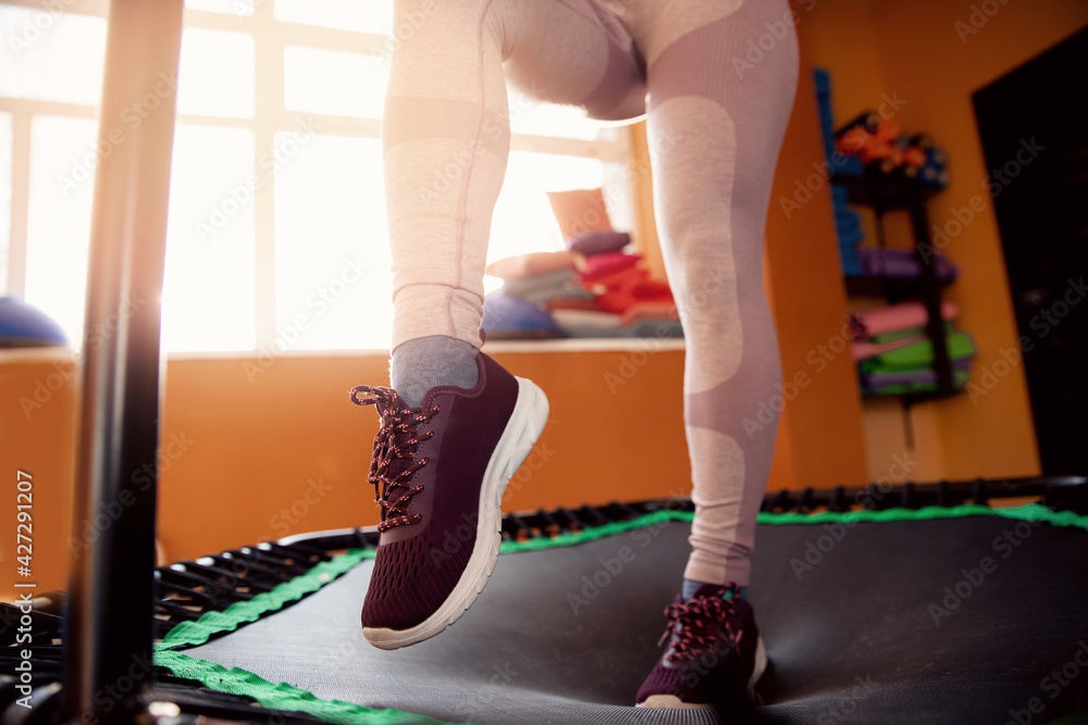 Wall mural closeup step fitness woman jumping on mobile mini trampoline