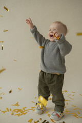 Little boy rejoice at the holiday. The boy has fun and throws some tinsel. Little kid has fun and enjoys the holiday