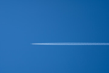 Airplane in flight with contrails in a clear blue sky